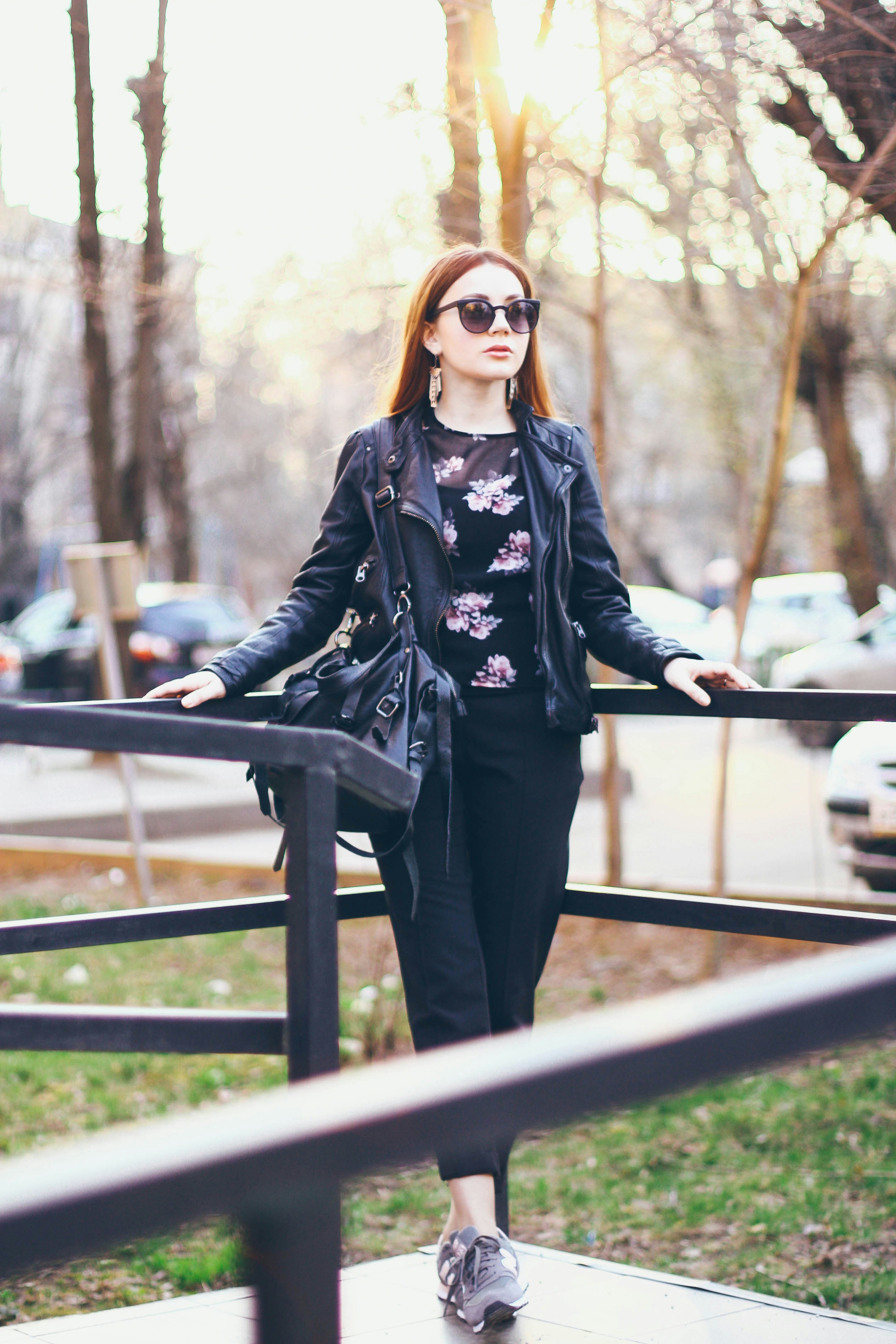 woman in black and white floral long sleeve shirt and black pants standing on bridge during